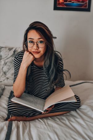 Girl with eyeglasses doing her homework in bed