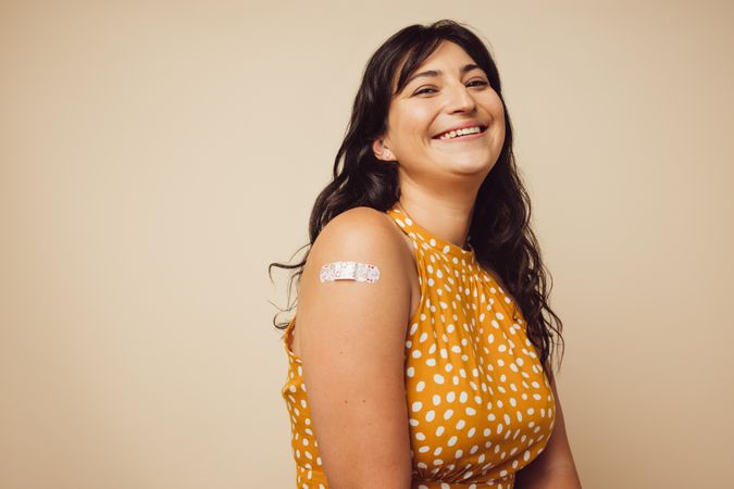 Woman smiling on brown background feeling happy to get inoculated