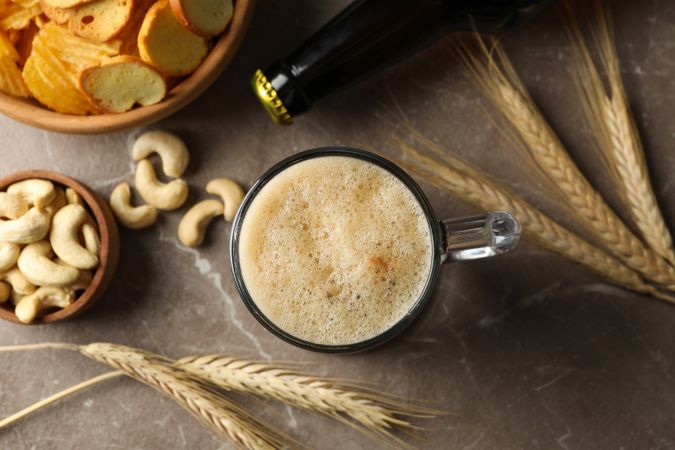 Beer, wheat and snacks on gray background, top view