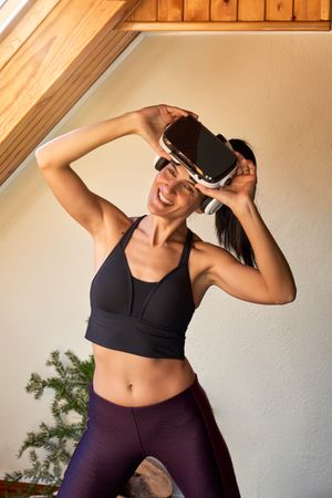 Positive slim woman doing exercises in VR glasses