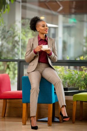 Woman in gray blazer holding a cup of coffee