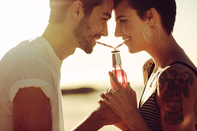 Close up of young couple in love drinking cold drink from same bottle