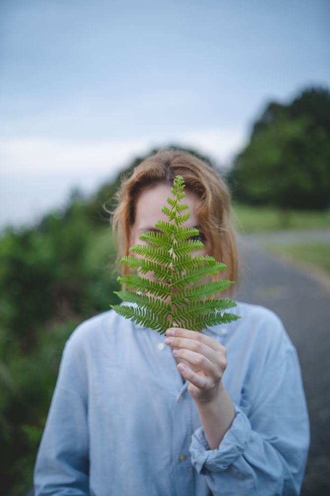 Woman holding fern leaf outdoors