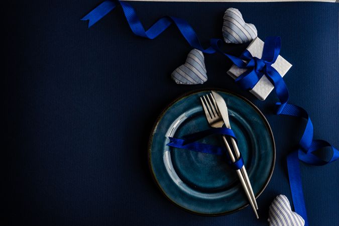 Valentine day table setting with blue plate and heart decoration and blue present