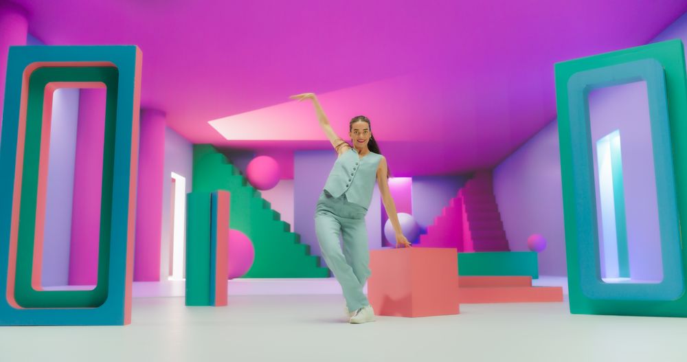 Woman with Bright Makeup Dancing Energetically in Colorful Geometric Abstract Environment. Creative Young Female Happily Performing Modern Dance Choreography in a Spacious Studio