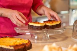 Crop person putting pieces of cake on glass dish