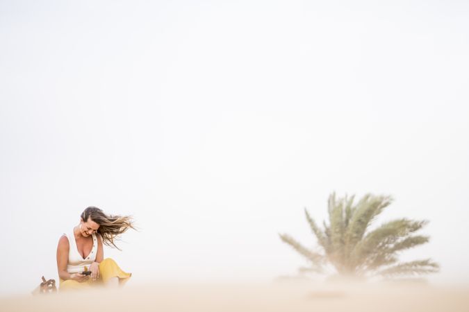Happy woman using smartphone in desert