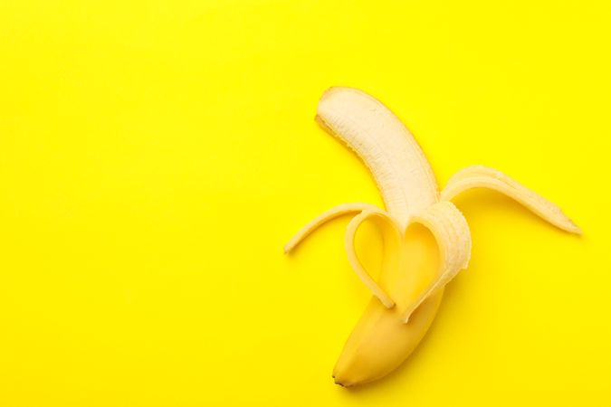 Heart made of banana on yellow background. Fresh fruit
