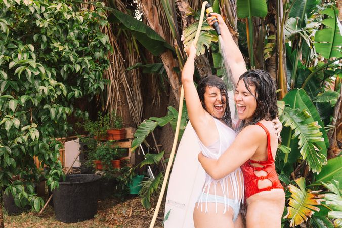 Girlfriends showering with hose in garden