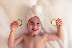 Happy boy with towel on head and cucumber slices