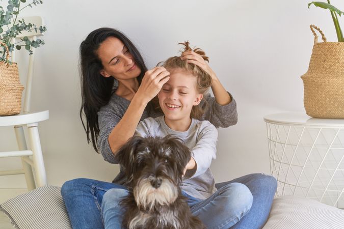 Mother doing hairstyle to positive boy