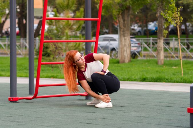 Woman squatting on outdoor fitness equipment