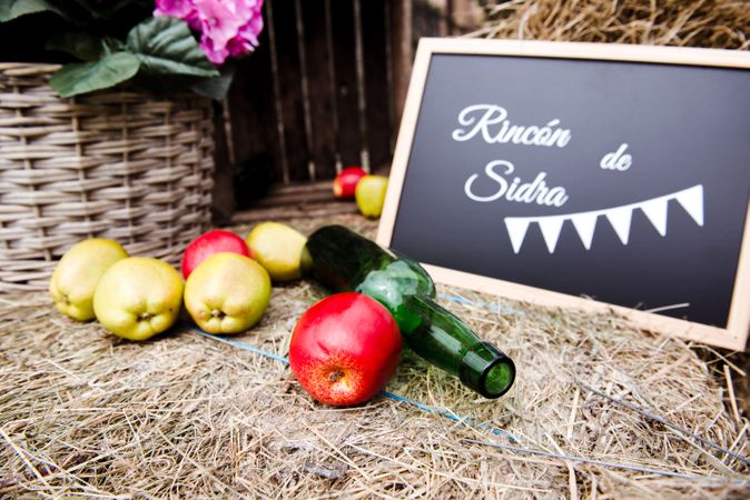 Apples near bottle and sign with inscription on hay