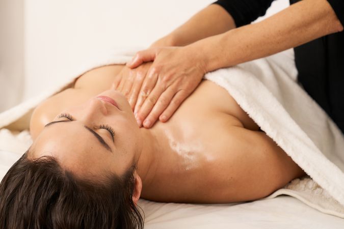 a woman massaging the chest of another woman lying on massage bed