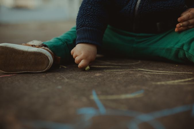 Toddler holding piece of yellow chalk