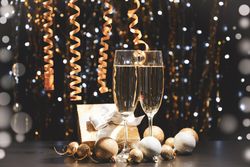 Christmas baubles and champagne glasses on blurred background, copy space
