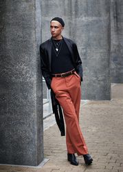 Fashionable young man leaning on concrete building