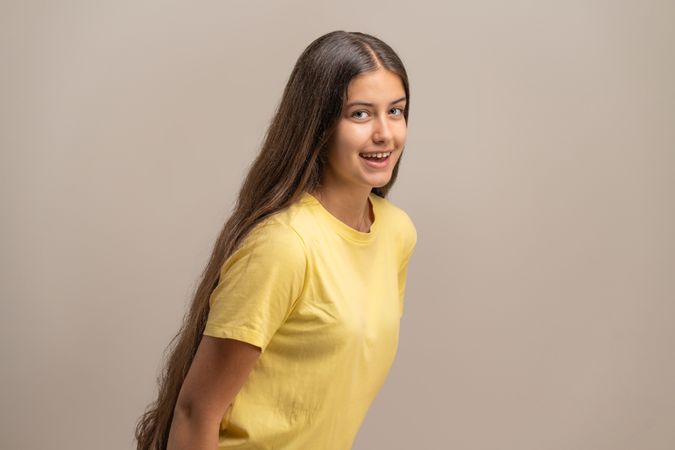 Happy young woman with long hair smiling and looking back at the camera.