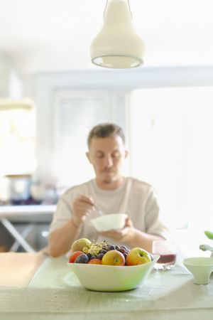 Man Chewing a Bite of Oats While Sitting an his Dinning Table.