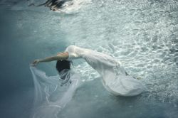 Woman in wedding dress floating underwater