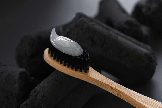 Close up of bamboo toothbrush with charcoal in background for natural oral hygiene