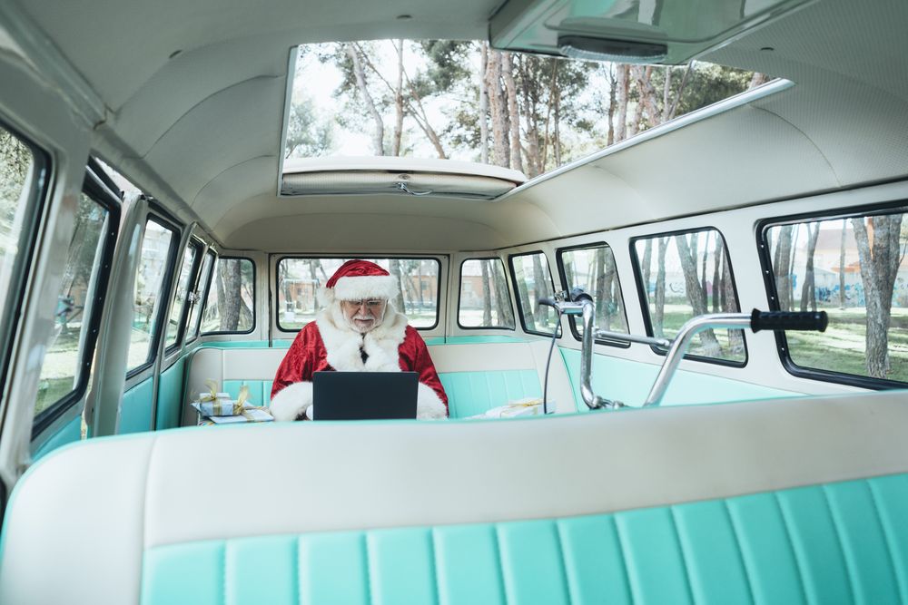 Santa Claus working at laptop in van