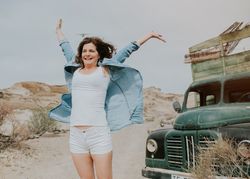 Cheerful female standing by old truck