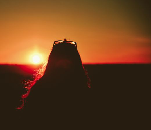 Silhouette of woman with sunglasses on her head  during sunset