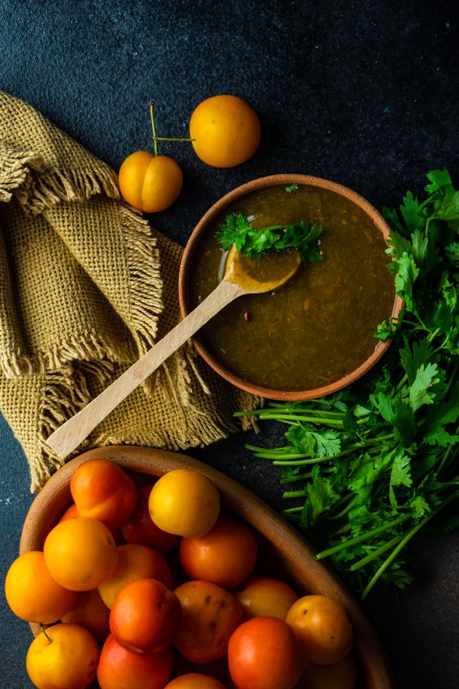 Top view of bowl of plums with parsley with Georgian Tkemali Sauce