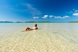 Woman resting in water on tropical seashore