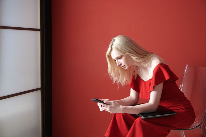 Young adult woman using smartphone and holding laptop