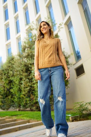 Woman in jeans and vest walking outside