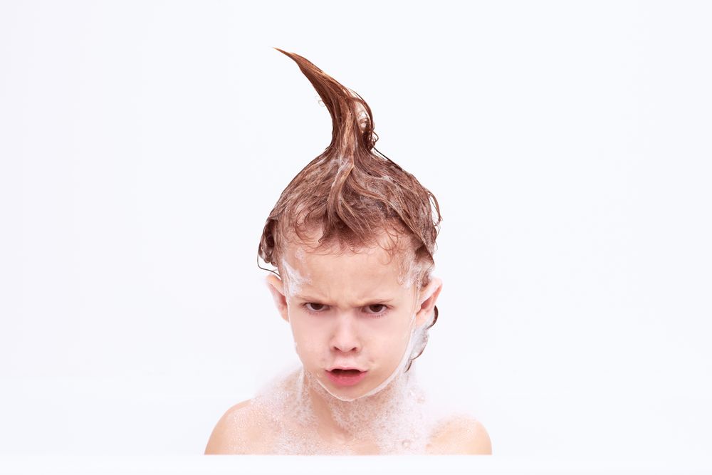 Grumpy boy with wet hair in mohawk in bathroom