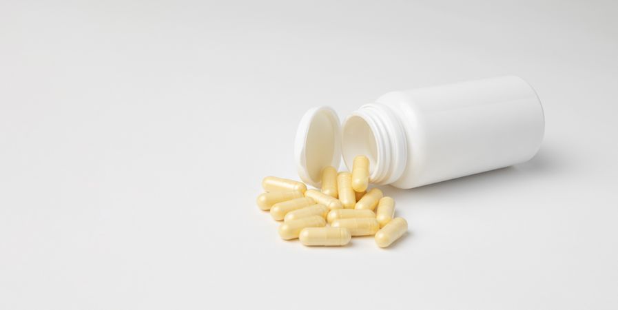 Mockup of a bottle of medicine capsules, or food supplement, lying down with copyspace