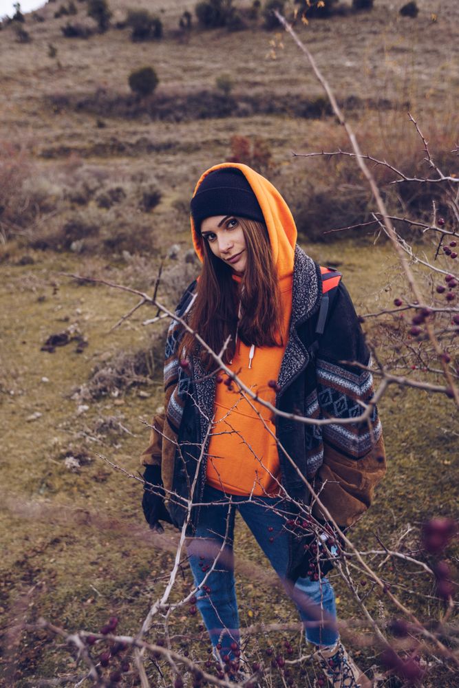 Hiker with backpack standing along pathway in autumn forest