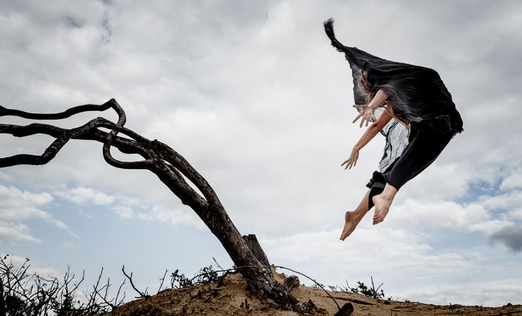 Woman posing in air near dry twigs and blue sky