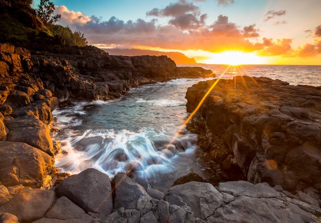 Waves crashing on rocks with sunrays