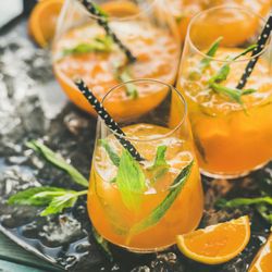 Orange cocktails in glass with garnish, and eco-friendly straws
