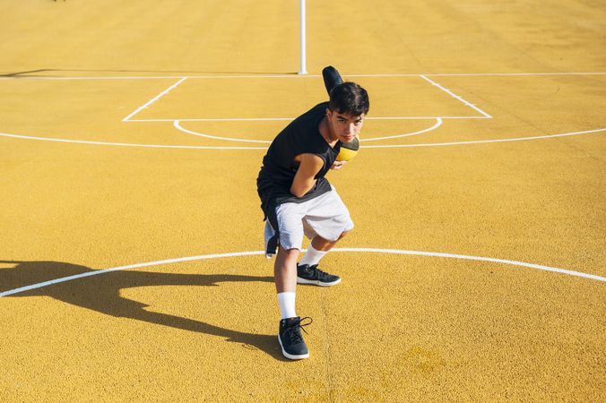 Young man playing on basketball court outdoor.