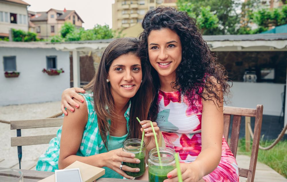 Two friends posing for photos with cocktails
