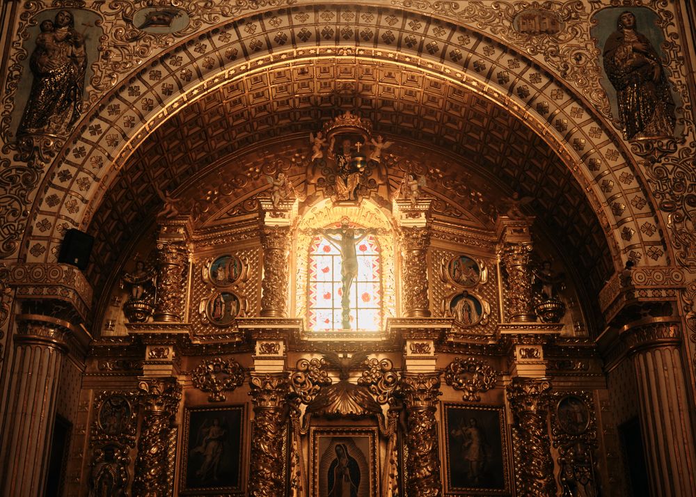 Crucifix in front of bright window on golden alter