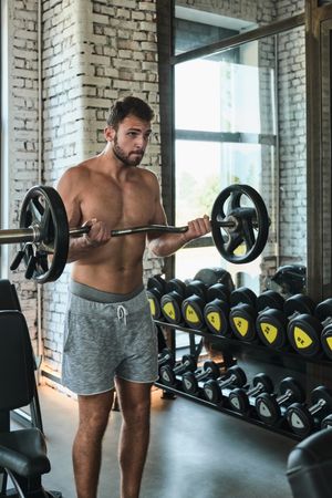 Bearded man exercising with barbell in gym