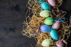 Easter card concept with pastel eggs in hay on wooden table
