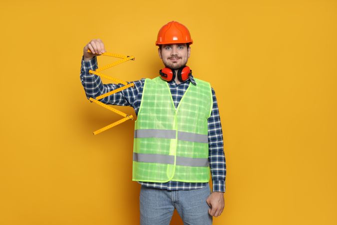 Young man civil engineer on yellow background