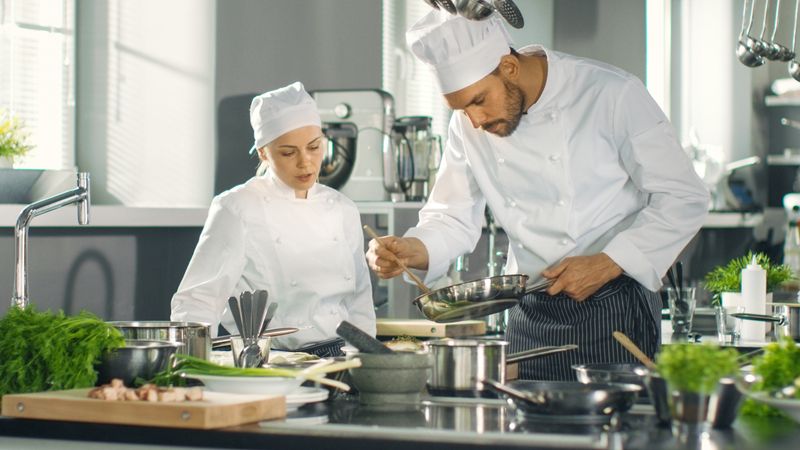 Famous Chef and His Female Apprentice Prepare Special Dish in a Modern Five Star Restaurant's Kitchen.