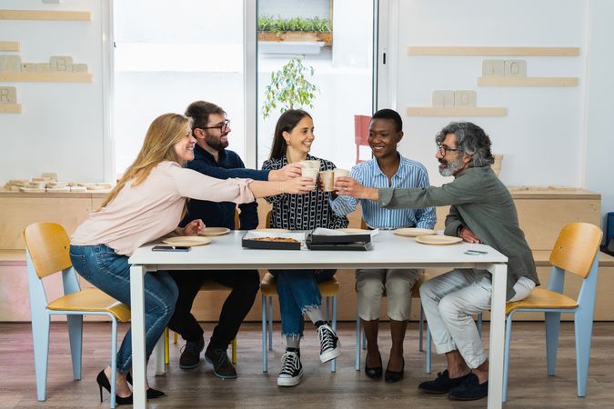 Colleagues having lunch together in kitchen of office