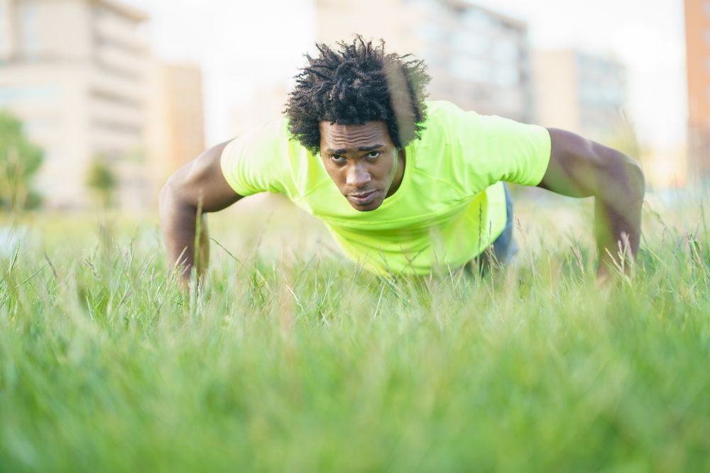Man in neon shirt doing pushups in park