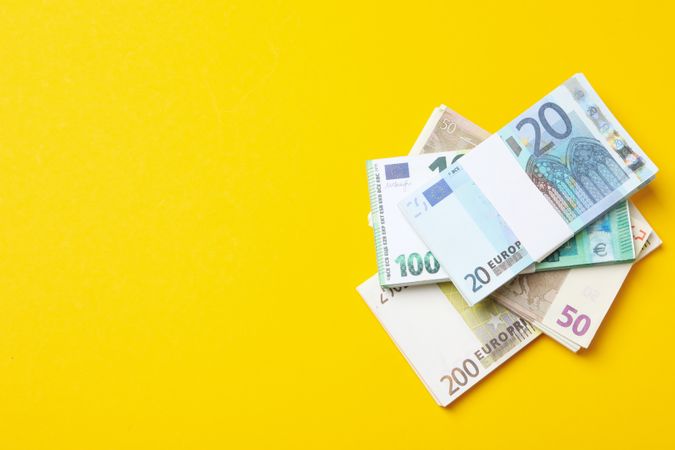 Many bundles of euros on a yellow background.
