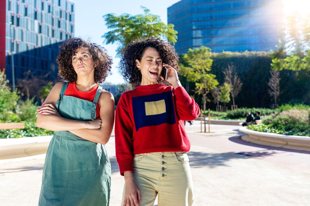 Woman speaking on phone while friend feels left out