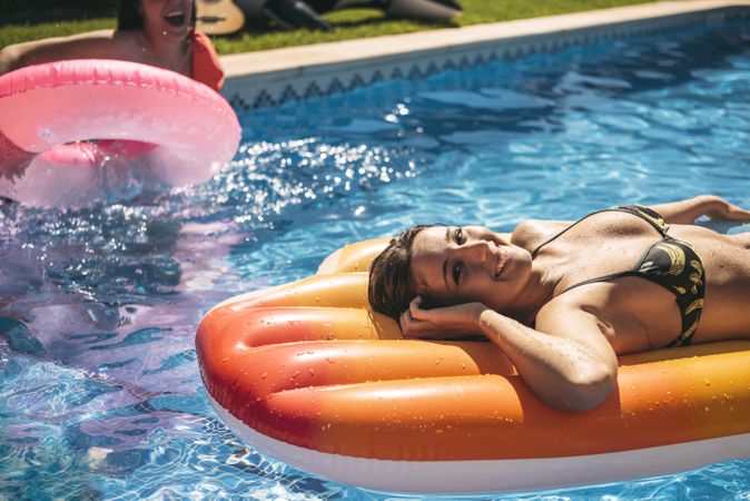 Young woman relaxing in pool with friends